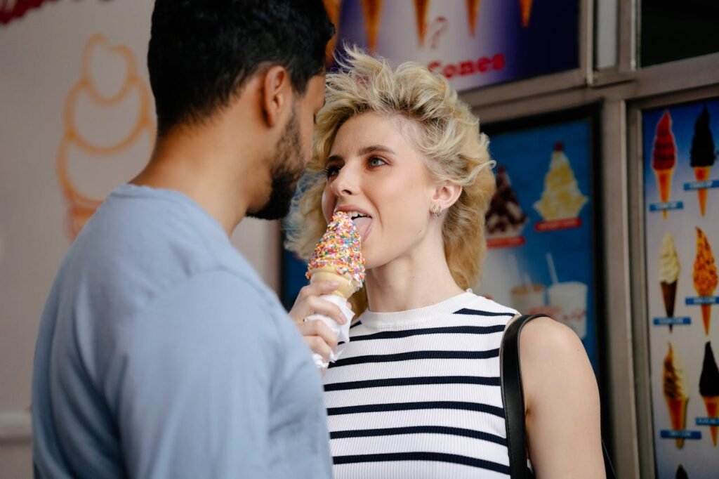 A couple playfully shares an ice cream cone with sprinkles, capturing a moment of romance and fun.